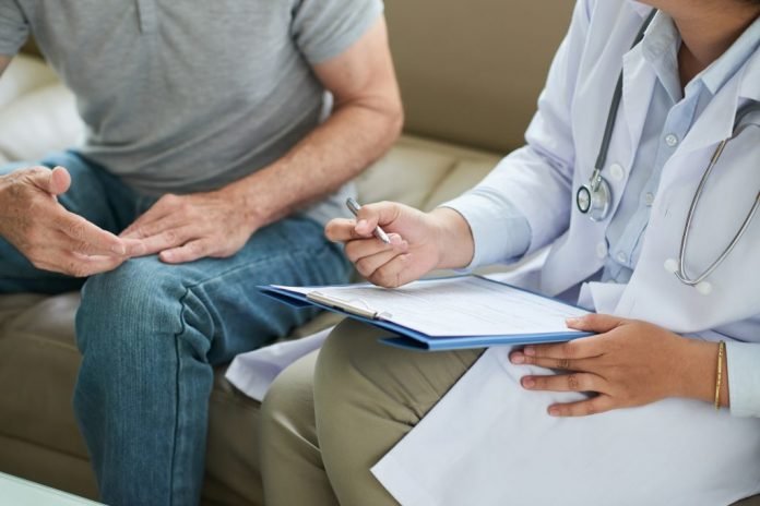 unrecognizable-female-doctor-sitting-on-couch-with-male-patient-and-filling-form-1024x683