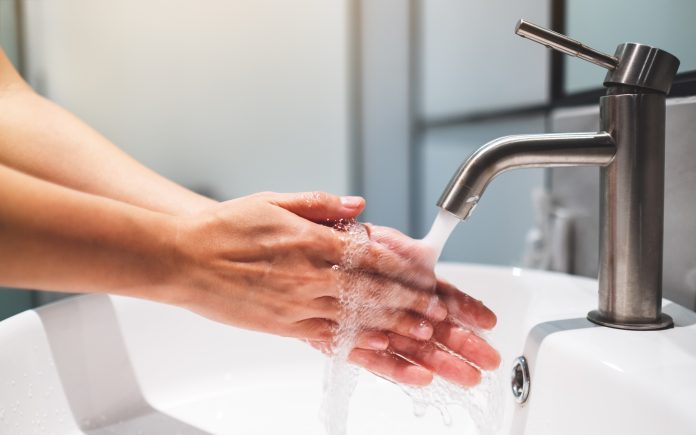 Woman cleaning and washing hands under the faucet in bathroom